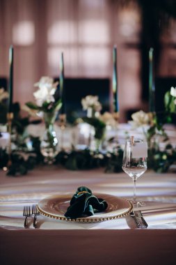 Sahne ışıkları altında altın ve yeşil renkli şık bir ziyafet masası.