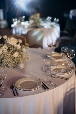 Beyaz ve yeşil elementlerle donatılmış şık bir düğün masası.