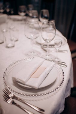 Beyaz bir tabak, beyaz peçete ve boncuklu şarj plakalı zarif bir masa.