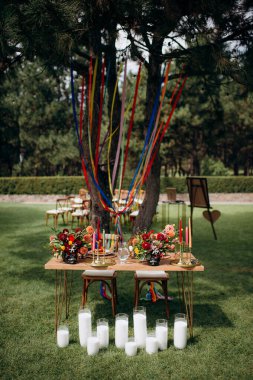 Açık havada, ahşap bir masası, renkli çiçekleri ve sandalye süslemeleri olan bir başkanlık.