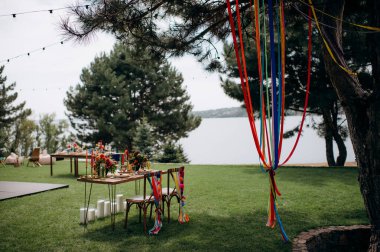 Açık havada, ahşap bir masası, renkli çiçekleri ve sandalye süslemeleri olan bir başkanlık.