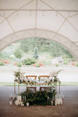 Altın çerçeveli, beyaz çiçekli bir çadırda zarif bir düğün başkanı.