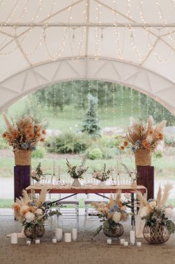 Pampa otları, kurumuş çiçekler ve sicim ışıkları olan bir çadırda zarif bir boho düğünü.