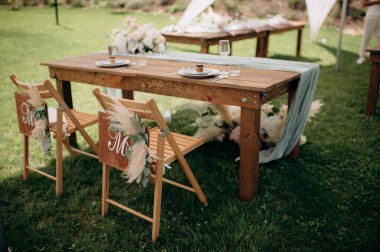Bay ve Bayan tabelaları ve otlarla süslenmiş ahşap sandalyeli kırsal açık hava düğün başkanlığı.