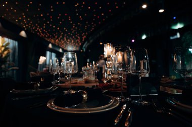 Yuvarlak masaları, siyah masa örtüleri, çiçekli süslemeleri ve mum ışığında zarif bir düğün resepsiyonu.