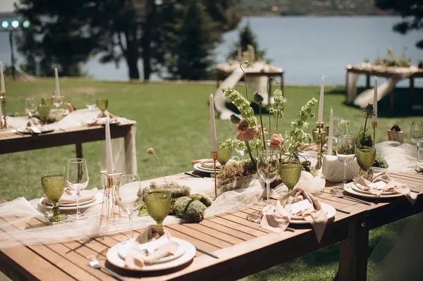 Açık yeşil keten peçeteyle bağlanmış şık bir açık hava masası.