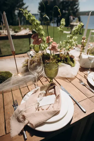 Açık yeşil keten peçeteyle bağlanmış şık bir açık hava masası.