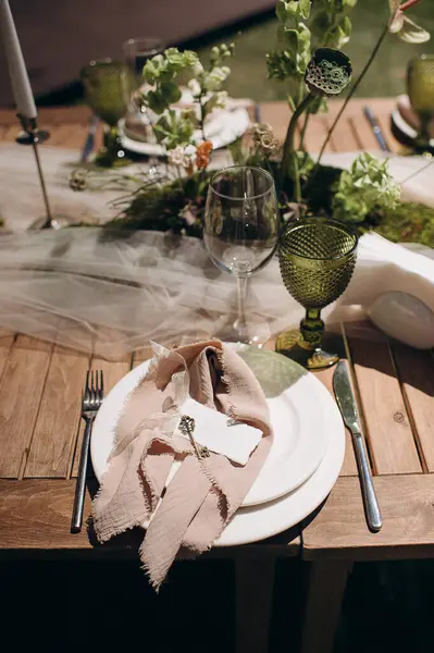 Açık yeşil keten peçeteyle bağlanmış şık bir açık hava masası.