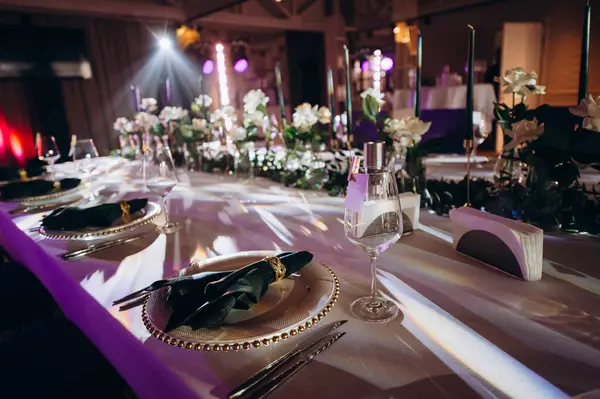 Sahne ışıkları altında altın ve yeşil renkli şık bir ziyafet masası.