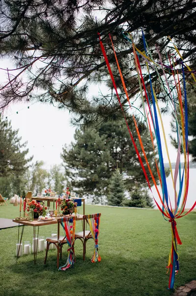 Açık havada, ahşap bir masası, renkli çiçekleri ve sandalye süslemeleri olan bir başkanlık.