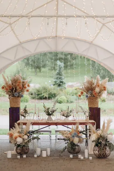 Pampa otları, kurumuş çiçekler ve sicim ışıkları olan bir çadırda zarif bir boho düğünü.
