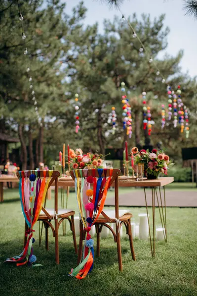 Renkli kurdeleleri, ponponları ve çiçek düzenlemeleri olan açık hava düğün başkanlığı.