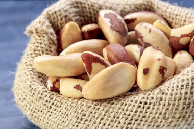 Çiğ Brezilya fındıklarını kırsal bir çuvala koyup doğal dokularını ve topraksı tonlarını sergiliyorlar. Boşluğu sola kopyala 