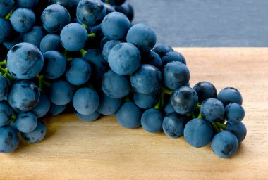 Ahşap bir yüzey üzerinde taze organik üzümlerin yakın çekimi, yiyecek, hasat ve doğal meyve temaları için idealdir. Boşluğu sağa kopyala 