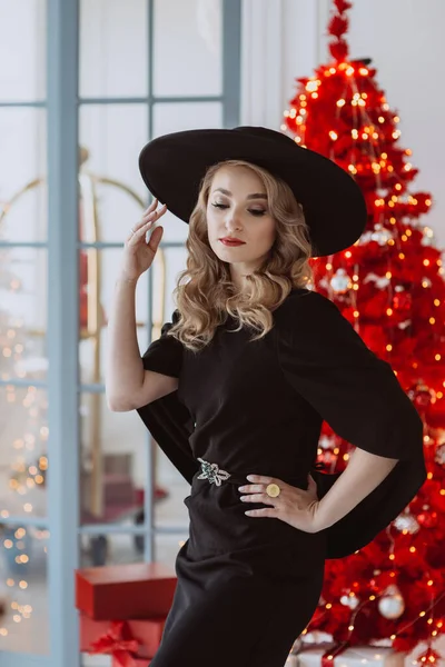 Hermosa Mujer Elegante Vestido Festivo Negro Sombrero Fondo Árbol Navidad —  Fotos de Stock