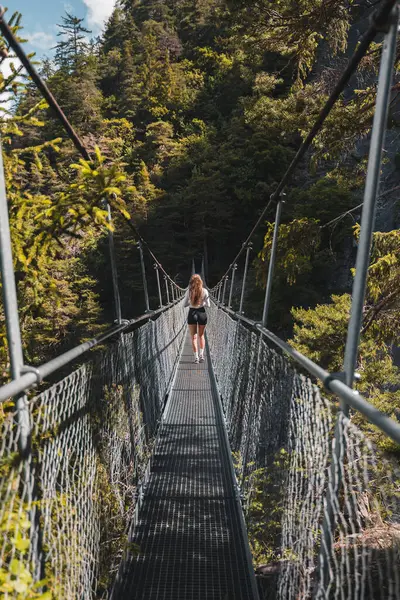 stock image Happy girl backpacker hiking on bridge in mountains and forest