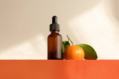 Portakal podyumunda koyu mat cam şişede C vitamini serumu, kopyalama alanı. Gölgeler ve güneş ışığı
