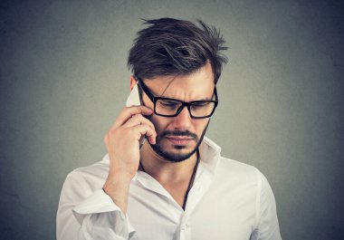 Cep telefonuyla konuşan mutsuz bir gencin yakın plan portresi. 