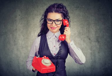 Gülümseyen mutlu genç bir kadın eski bir telefonda konuşuyor. 