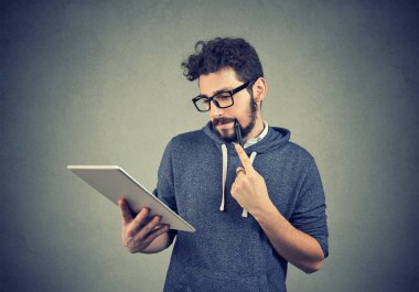 Tablet bilgisayar kullanan düşünceli bir adam. 