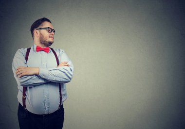 Kendine güvenen eksantrik iş adamı ayakta duruyor ve yana bakıyor. 