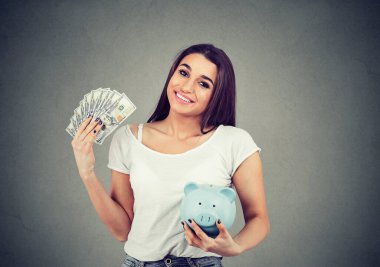 Dolar banknotları ve kumbarası olan gülümseyen kadın.