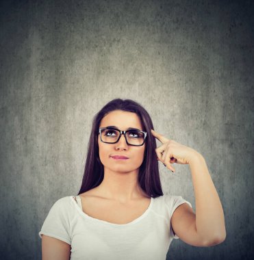 Düşünme çapraşık kadın ararken gri duvar arka plan üzerinde izole. Bir problem çözme kafa çizilmemesi düşünceli kız