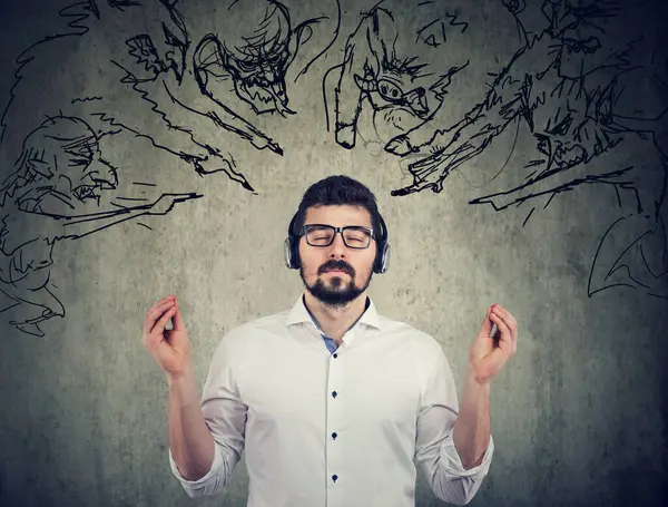 stock image Stress free man meditating listening to music not listening  to angry evil people screaming at him