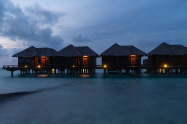 Mavi saatte, Maldivler 'deki bir adada gölgeli su villalarının güzel manzarası..