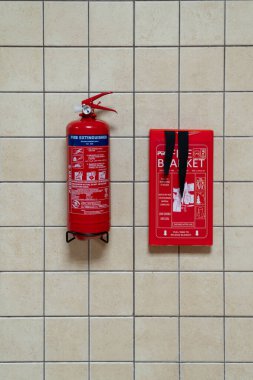 Dubai, United Arab Emirates - 5th July, 2023 : View of a fire extinguisher and blanket mounted on a tiled wall in the kitchen of a residential apartment for emergency use. clipart