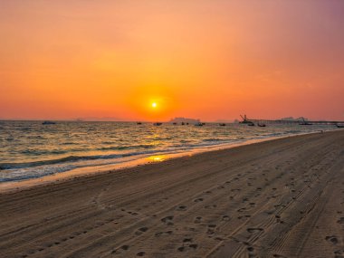 Tayland 'ın Krabi eyaletindeki Klong Muang plajında ateşli kırmızı tropikal gün batımı. Denizde uzun kuyruklu tekneler.