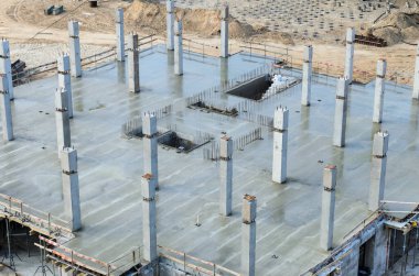 Construction site. The construction of a new house, above view on a freshly poured concrete ceiling and frame pillars. In the background is a pile field in a pit 