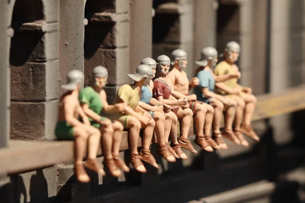 Figures of people sitting on the ledge of a house