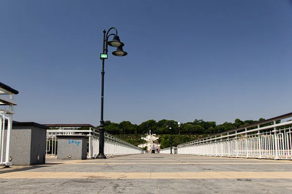 Önünde sokak lambası olan deniz kıyısındaki güzel bir rıhtım manzarası. Bulutsuz mavi gökyüzü ile güneşli bir yaz günü. Yaz tatili
