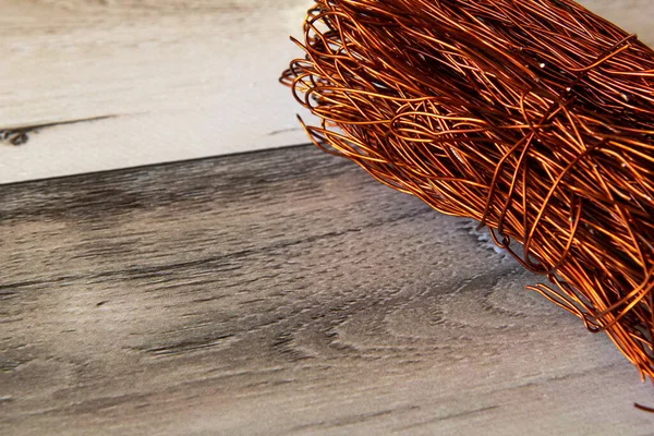 Ahşap bir arka planda, güneş ışığıyla bükülmüş büyük bakır tel. Boşluğu kopyala 