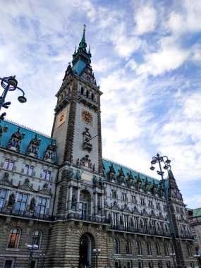 Üzerinde bulutlu güzel gökyüzü olan Hamburg Belediye Sarayı 'nın dikey fotoğrafı. Etkileyici mimari ve şehir simgesi güpegündüz yakalandı..