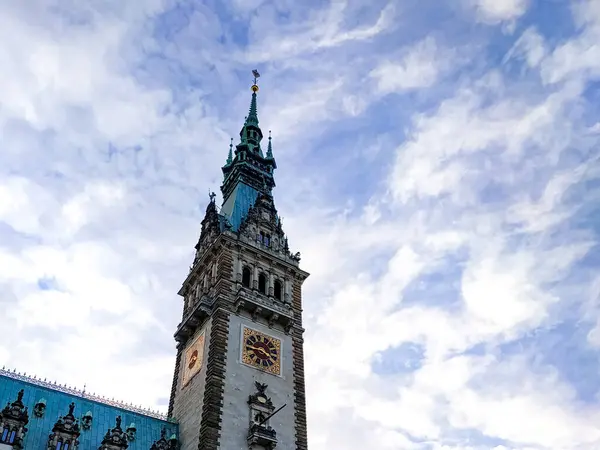 Hamburg Belediye Binası güneşli bir günde açık mavi gökyüzü ve arka planda beyaz bulutlar. Şehrin kalbinde tarihi mimari.