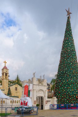 Nazareth, Israel - January 06, 2023: View of the church (Mary well) square, with the Greek Orthodox Church of the Annunciation, and a Christmas tree, on Orthodox Christmas Eve, in Nazareth, Israel