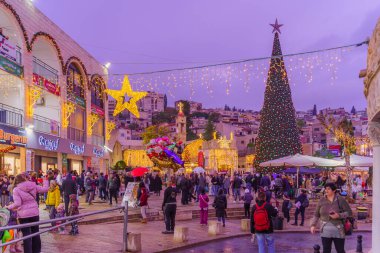 Nazareth, Israel - January 06, 2023: Scene of the church (Mary well) square, with Greek Orthodox Church of the Annunciation, Christmas tree, and crowd, on Orthodox Christmas Eve, in Nazareth, Israel