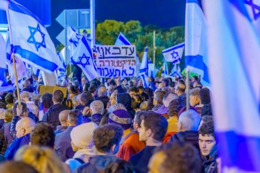 Haifa, Israel - January 21, 2023: Crowd of people protest with various signs and flags against the plans of the new government, claiming its anti-democratic, in Haifa, Israel