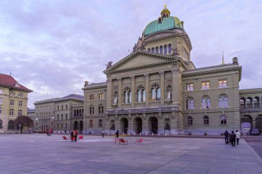 Bern, İsviçre - 23 Şubat 2023: Parlemento Binası 'nın (Bundeshaus) yerli halk ve ziyaretçilerle birlikte Bern, İsviçre' de gün batımı manzarası