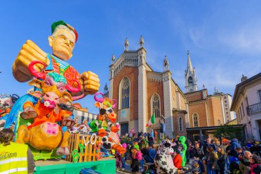 Cantu, İtalya - 25 Şubat 2023: Karnaval geçidi, İtalyan İnek figürlü vagon, kalabalık ve Aziz Michael ve Blaise Kilisesi, Cantu, Lombardy, Kuzey İtalya