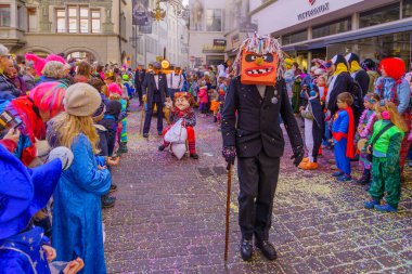 Lucerne, İsviçre - 21 Şubat 2023: Kostüm giymiş bir grup katılımcı ve kalabalık, İsviçre 'nin Lucerne kentinde düzenlenen Fasnacht Karnavalı' nın çocuk geçit töreninin bir parçası.