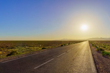 Arka planda Atlas Dağları olan bir çöl yolu manzarası. Merkez Fas