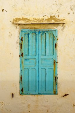 Mavi pencereler ve panjurlar beyaz boyalı eski bir evin duvarında. Essaouira (Mogador), Fas