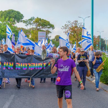 Hayfa, İsrail - 10 Haziran 2023: İnsanlar bayraklar ve çeşitli işaretlerle yürüyor. Hayfa, İsrail 'de hükümet karşıtı gösterilerin 23. haftası