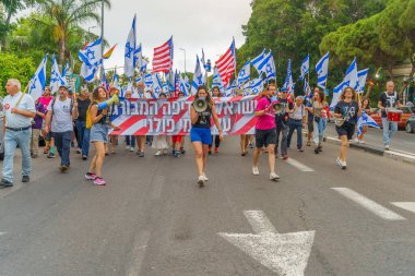 Hayfa, İsrail - 17 Haziran 2023: İnsanlar bayraklar ve çeşitli işaretlerle yürüyor. Hayfa, İsrail 'de 24 haftalık hükümet karşıtı protesto