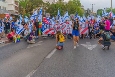 Hayfa, İsrail - 17 Haziran 2023: İnsanlar bayraklar ve çeşitli işaretlerle yürüyor. Hayfa, İsrail 'de 24 haftalık hükümet karşıtı protesto