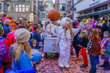 Lucerne, İsviçre - 21 Şubat 2023: Kostüm giymiş bir grup katılımcı ve kalabalık, İsviçre 'nin Lucerne kentinde düzenlenen Fasnacht Karnavalı' nın çocuk geçit töreninin bir parçası.