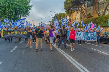 Hayfa, İsrail - 8 Temmuz 2023: İnsanlar bayraklar ve çeşitli işaretlerle yürüyor. Hayfa, İsrail 'de 27 haftalık hükümet karşıtı protesto